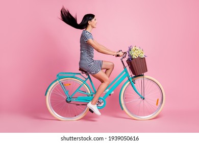 Full length body size profile side view of pretty cheerful girl riding bike having fun isolated on pink pastel color background