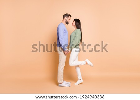 Full length body size profile side view of nice amorous couple soulmates meet holding hands isolated on beige pastel color background