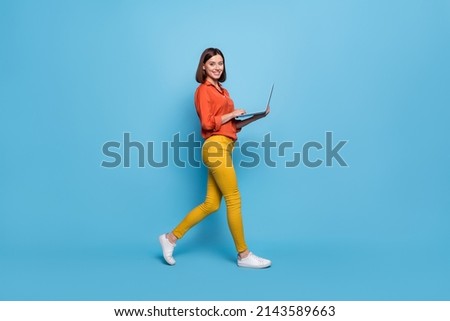 Full length body size profile side view of attractive cheery girl going using laptop isolated over bright blue color background