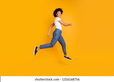 Full length body size side profile photo jumping high beautiful she her lady rushing black friday sale shopping store mall wearing casual jeans denim white t-shirt clothes isolated yellow background