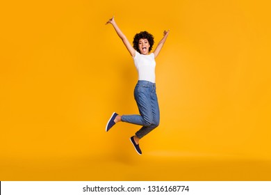 Full length body size side profile photo jumping high beautiful she her lady hands arms up win game play match wearing casual jeans denim white t-shirt clothes isolated yellow bright vivid background