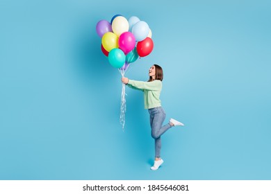 Full length body size side profile photo of cheerful happy girl looking up standing tiptoe keeping balloons smiling isolated on vivid blue color background