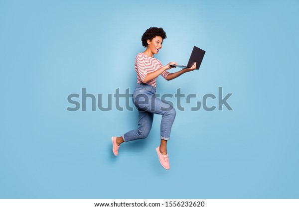 ノートパソコンがジーンズの縞模様のシャツを着て パステルの色の青の背景にパステルを着て かなり明るいかわいい魅力的な若者がタイプする 全長のボディサイズのサイドプロファイル写真 の写真素材 今すぐ編集