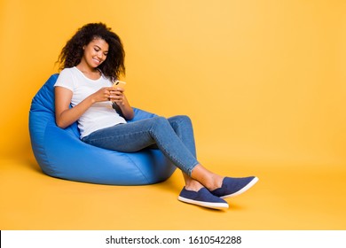 Full length body size turned photo of cheerful curly wavy brown haired positive girl browsing through her phone answering in comments of her repost isolated over vivid color background - Powered by Shutterstock