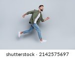 Full length body size view of attractive cheerful active guy jumping running isolated over grey pastel color background