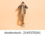 Full length body size view of attractive cheerful guy posing touching specs isolated over beige pastel color background