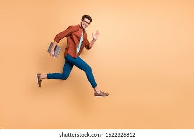 Full length body size view of his he nice attractive cheerful cheery glad content guy jumping in air carrying laptop running fast late hurry-up meeting isolated over beige color pastel background
