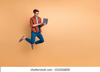 Full length body size view of his he nice attractive cheerful cheery successful brunet guy jumping in air using laptop home-based job isolated over beige color pastel background - Shutterstock ID 1522326830