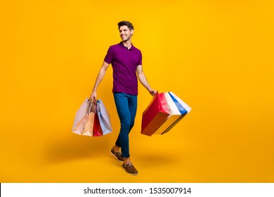 Full length body size view of his he nice attractive cheerful cheery glad content guy carrying new things colorful packages isolated over bright vivid shine vibrant yellow color background