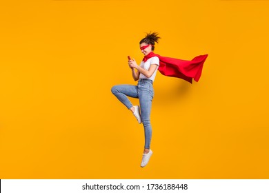 Full length body size view of her she nice attractive lovely cheerful focused girl jumping wearing cape using digital device 5g app isolated on bright vivid shine vibrant yellow color background
