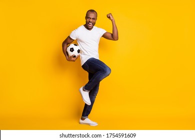 Full length body size view of his he nice attractive lucky cheerful cherry guy holding in hand ball soccer having fun isolated over bright vivid shine vibrant yellow color background - Powered by Shutterstock