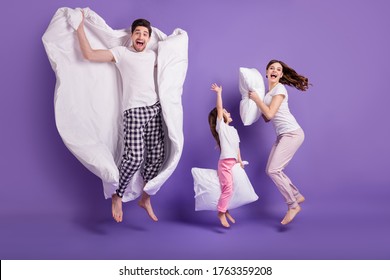 Full length body size view of cheerful glad crazy family small little daughter jumping carrying pillow duvet having fun bedtime isolated on bright vivid shine vibrant violet color background