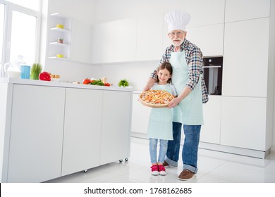 Full length body size view of cheerful grey-haired grandparent grandchild holding in hands tray baked domestic vegetarian pizza mushroom workshop help support in light white interior kitchen house - Powered by Shutterstock