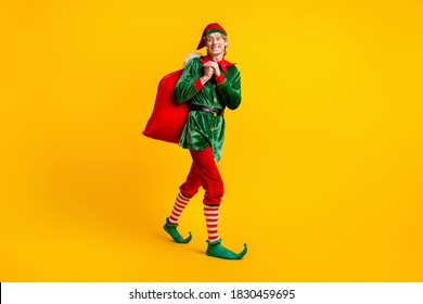 Full length body size view of his he nice attractive cheerful funny guy elf going carrying bringing sack gifts delivery Eve Noel isolated over bright vivid shine vibrant yellow color background