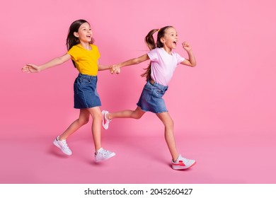 Full length body size view of two pretty cheerful girls holding hands jumping running isolated over pink pastel color background - Shutterstock ID 2045260427