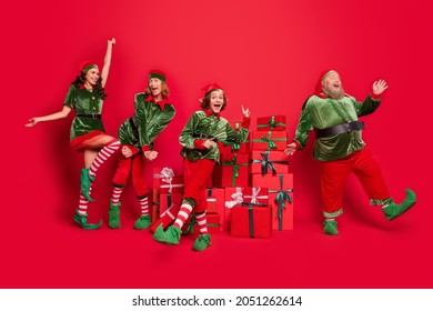 Full length body size view of cheerful friends elf having fun festal sale boxes dancing isolated over bright red color background