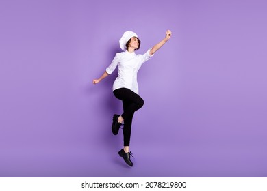 Larga vista del tamaño corporal del agradable y alegre chef saltando aislado sobre un fondo violeta violeta brillante de color