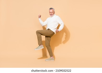 Full length body size view of attractive cheerful grey-haired man dancing fooling isolated over beige pastel color background