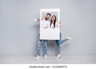 Full length body size view of attractive cheery couple holding photo frame having fun isolated over grey pastel color background - Shutterstock ID 2113649573