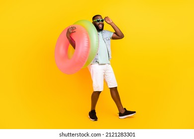 Full length body size view of attractive trendy cheery guy carrying life buoy having fun isolated over bright yellow color background