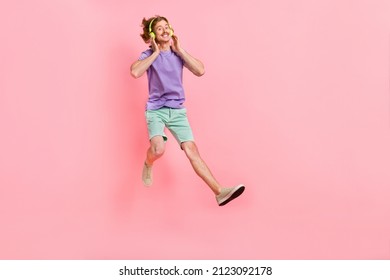 Full Length Body Size View Of Attractive Cheerful Guy Jumping Listening Hit Song Isolated Over Pink Pastel Color Background