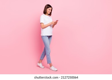 Full length body size view of attractive cheerful girl going using device browsing web isolated over pink pastel color background - Shutterstock ID 2127250064