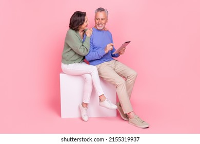 Full Length Body Size View Of Two Attractive Cheery People Sitting On Box Using Device Isolated Over Pink Pastel Color Background