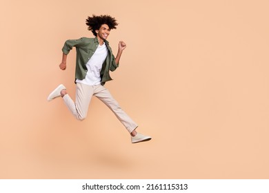 Full length body size view of attractive cheerful energetic guy jumping running isolated over beige pastel color background - Shutterstock ID 2161115313