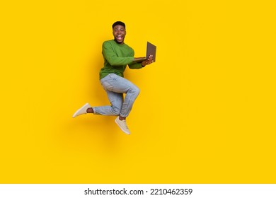 Full length body size view of attractive guy jumping using laptop web isolated over vivid yellow color background
