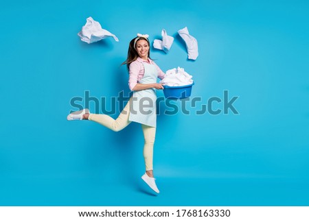 Full length body size view of her she nice attractive cheerful cheery girl maid jumping holding in hand laundry bowl throwing things isolated on bright vivid shine vibrant blue color background