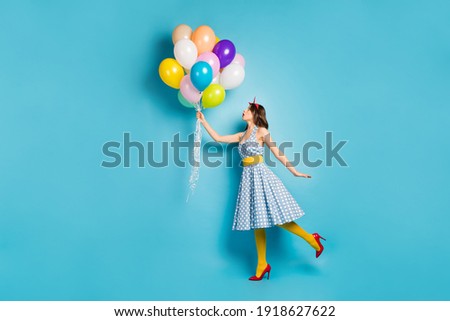 Full length body size view of her she nice attractive dreamy fashionable wavy-haired girl holding air balls flying up walking having fun isolated on bright vivid shine vibrant blue color background