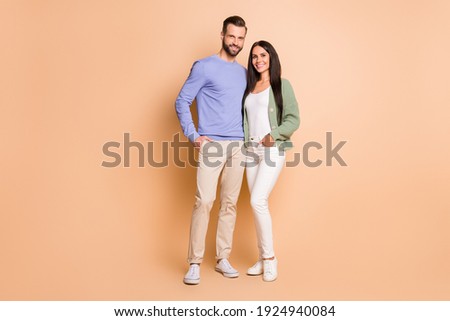 Full length body size view of attractive cheerful couple soulmates embracing isolated over beige pastel color background