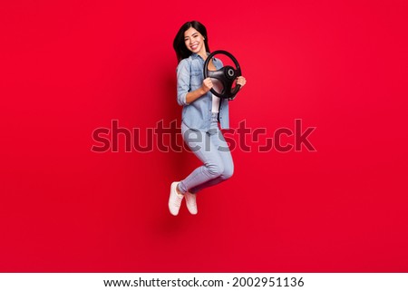 Full length body size view of pretty cheerful girl jumping holding steering wheel way trip isolated over bright red color background
