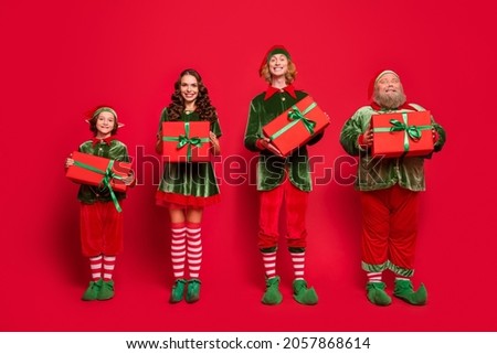 Full length body size view of attractive cheerful company elf holding dream boxes isolated over bright red color background