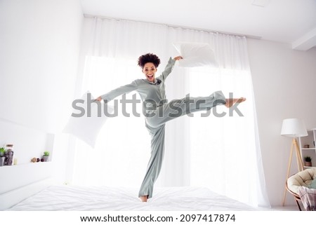 Full length body size view of attractive cheerful ecstatic crazy girl dancing on bed fooling at light white home indoors