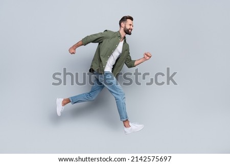 Full length body size view of attractive cheerful active guy jumping running isolated over grey pastel color background