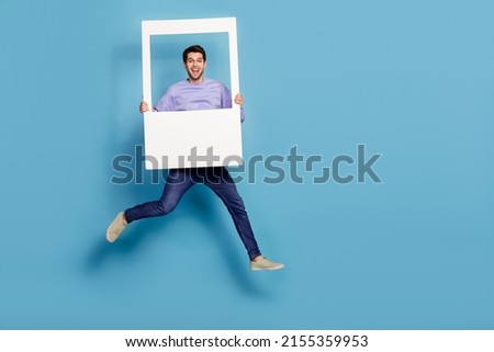 Full length body size view of attractive cheery guy jumping holding photo frame window isolated over bright blue color background