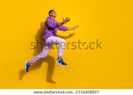 Full length body size view of handsome trendy cheerful guy jumping catching copy space isolated on vivid yellow color background