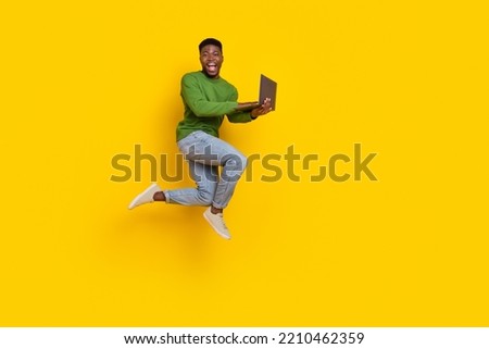 Full length body size view of attractive guy jumping using laptop web isolated over vivid yellow color background