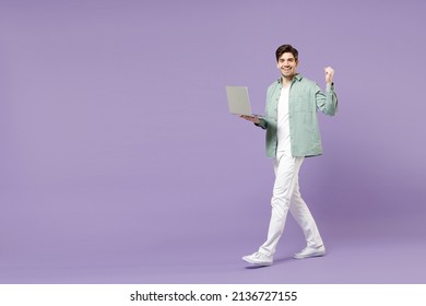 Full length body young fun happy smiling man in casual mint shirt white t-shirt use laptop pc computer do winner gesture clench fist walk isolated on purple background studio. People lifestyle concept - Powered by Shutterstock