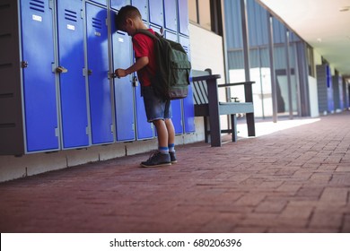 Full length of boy leaning on lockers in corridor at school - Powered by Shutterstock