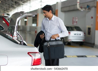 Full Length Of Businessman Unloading Luggage From Car Boot At Airport Terminal

