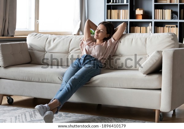 Full\
length calm woman with closed eyes resting on cozy couch, leaning\
back, enjoying lazy leisure time, attractive peaceful young female\
relaxing, daydreaming, taking nap on sofa at\
home