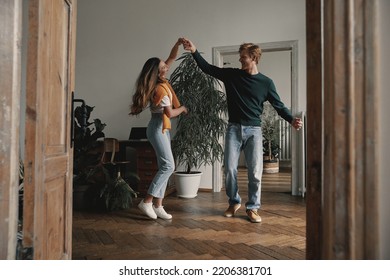 Full length of carefree young couple dancing at home together - Shutterstock ID 2206381701