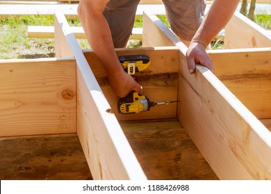 Full length carpenter drilling wood at construction site