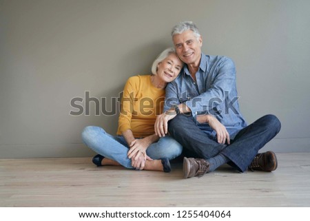  Full length of casual modern senior couple sitting on floor on background                              