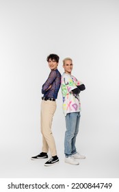 Full Length Of Cheerful Gay Man And Queer Person Standing Back To Back With Crossed Arms On Grey Background