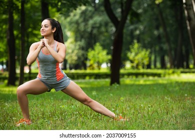 Full Length Of Cheerful Sportswoman Doing Squat Exercise In Park