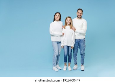 Full Length Of Cheerful Young Happy Parents Mom Dad With Child Kid Daughter Teen Girl In Casual White Sweaters Hugging Isolated On Blue Color Background Studio Portrait. Family Day Parenthood Concept