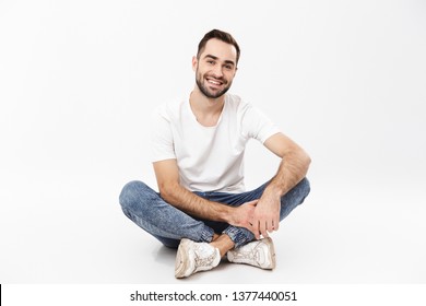 Full length of a cheerful young man sitting with legs crossed isolated over white background
